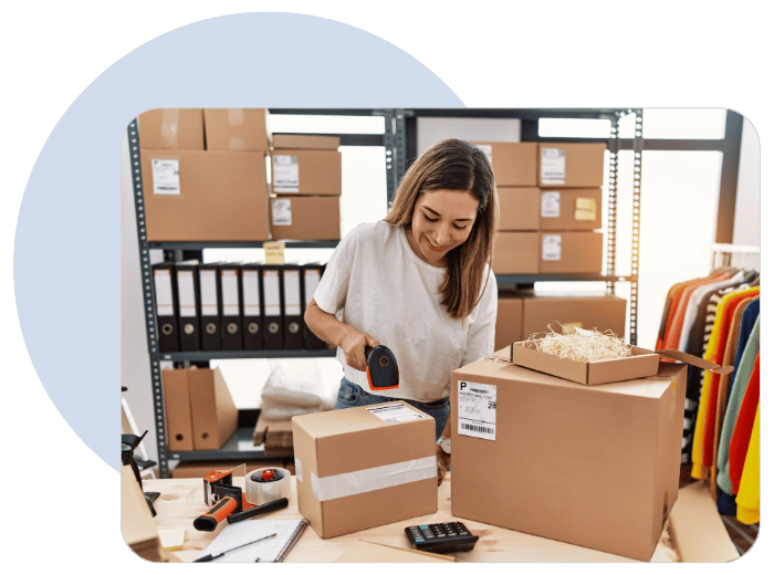 woman sticking a label on a box with computer next to her